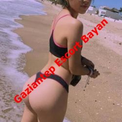 Woman in a black and pink bikini on a sandy beach by the water, with red diagonal text 'Gaziantep Escort Bayan' across the image.