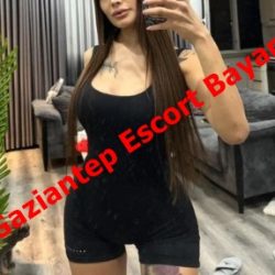 Woman in a black sleeveless outfit taking a mirror selfie in a modern living room; bold red overlay reads Gaziantep Escort Bayan.